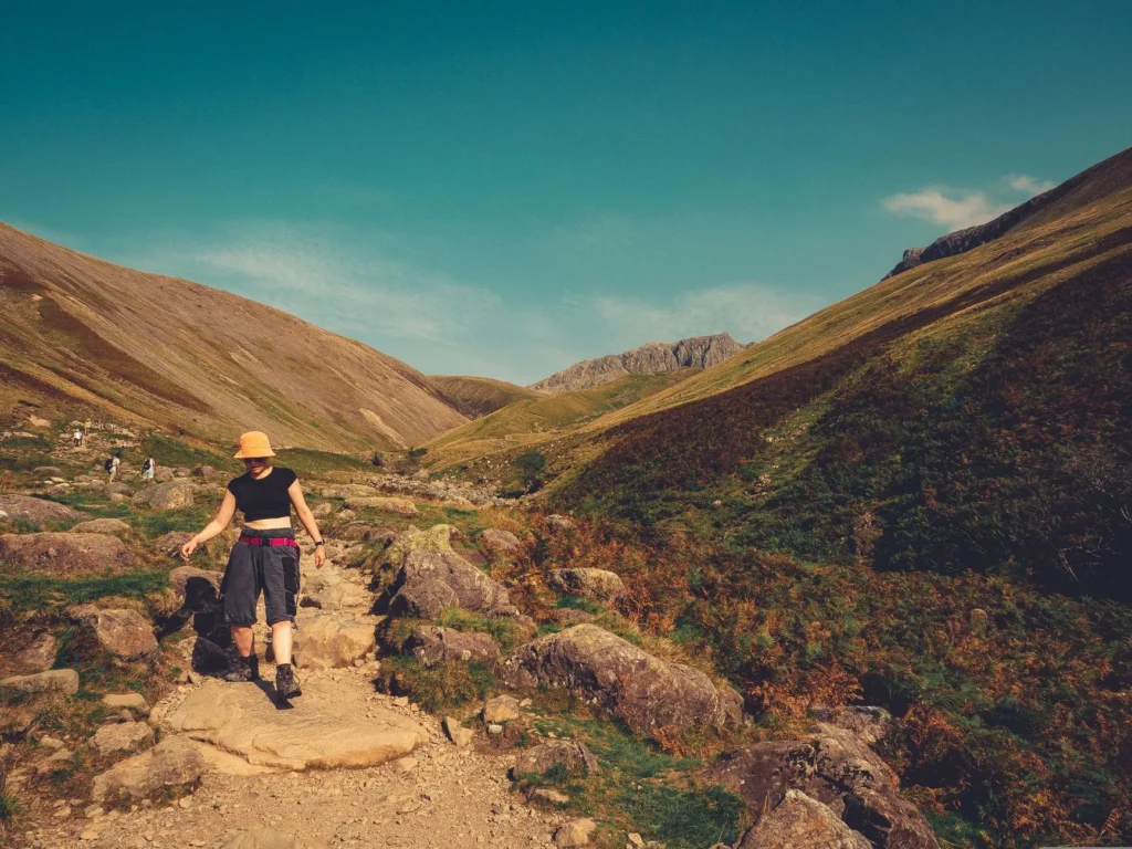 Sentier de randonnée en montagne dans les Alpes françaises, avec prairie alpine et sommets enneigés en arrière-plan